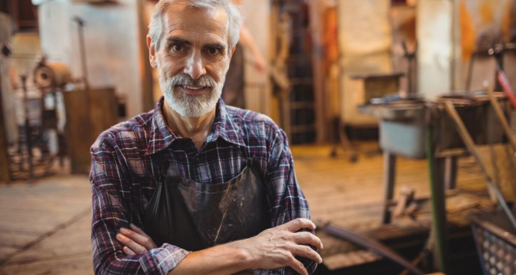 Portrait of glassblower standing with arms crossed at glassblowing factory